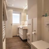 Das Bad im schönen Naturdesign ist mit modernen Sanitärobjekten und mit Fußbodenheizung ausgestattet. Ein Waschtisch mit Schubladen bietet Platz für alle Badutensilien.